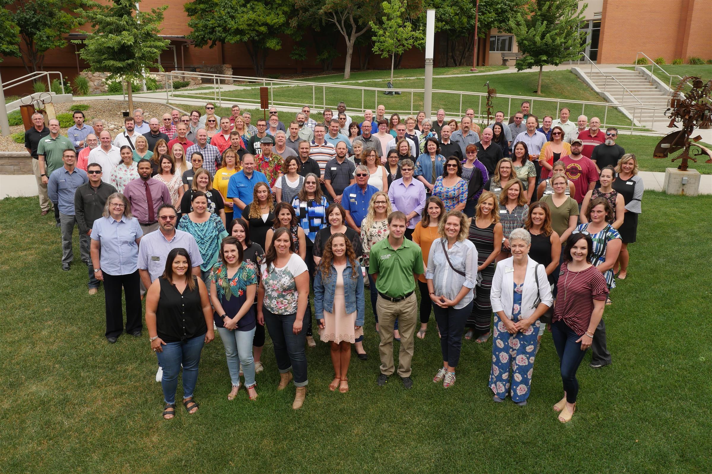 2018年夏天，100多名教职员工站在院子的草地上